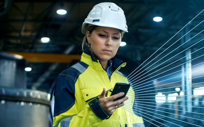 Frau in gelbem Arbeitsanzug hält Handy in der Hand